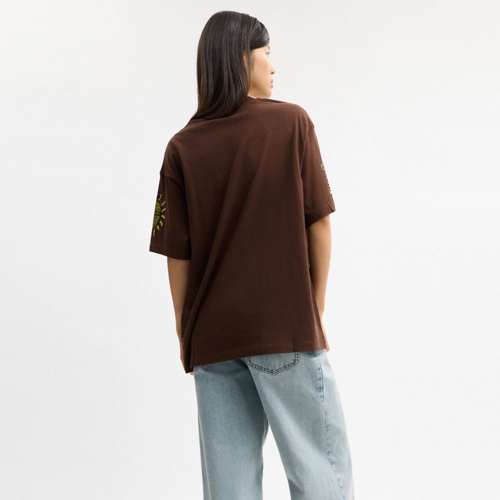 COACH®,Coach Graphic Relaxed T-Shirt In Organic Cotton,Organic Cotton,T Shirt,Logo,Casual,Brown,Scale View